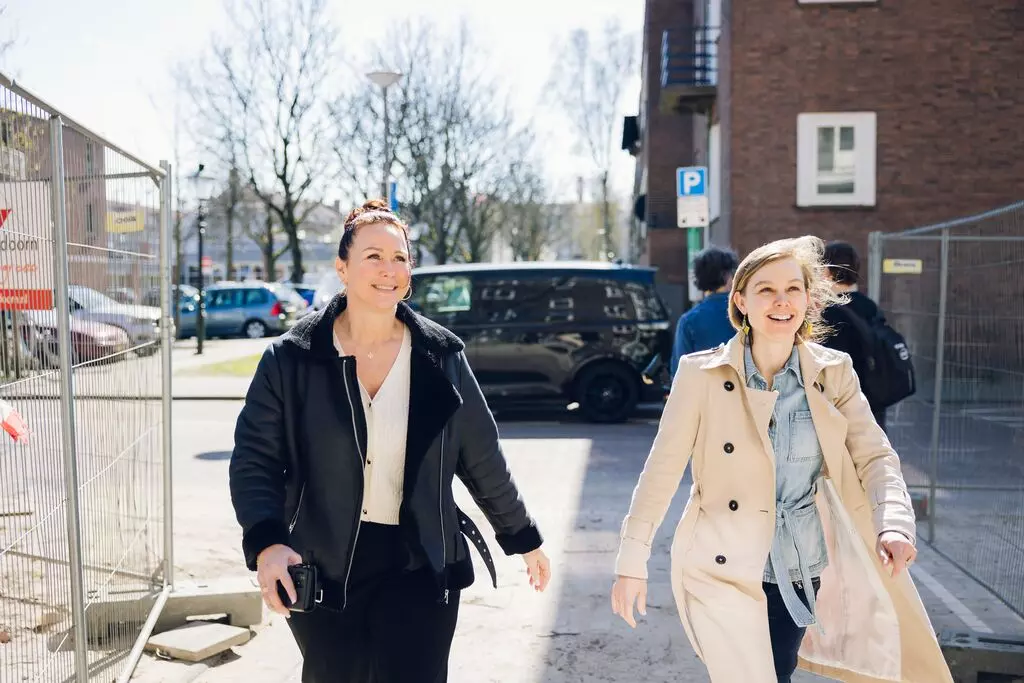 Collega’s van Woonstad Rotterdam staand in overleg tijdens een teammeeting in een lichte vergaderruimte.