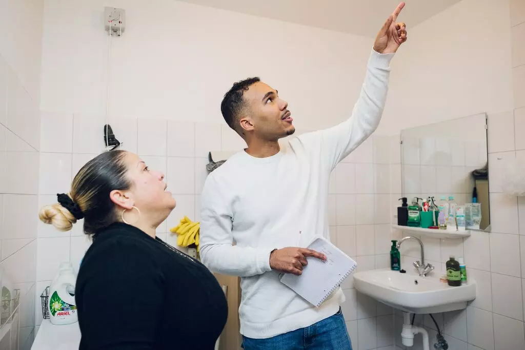 Medewerker Dagelijks Onderhoud in gesprek met bewoner voor reparatiebezoek.