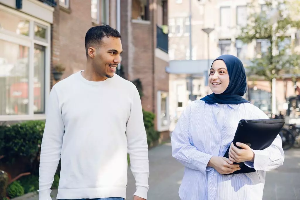 Lachende collega van de afdeling Dagelijks Omnderhoud van Woonstad Rotterdam maken een wandeling.