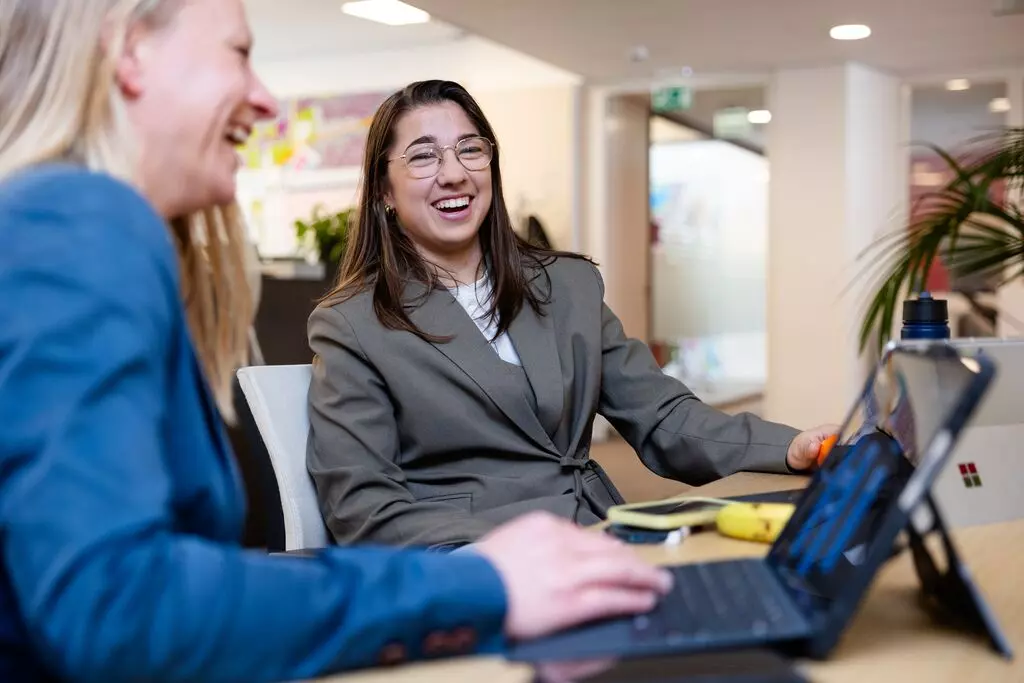 Annebel Wanschers Twee collega’s van Woonstad Rotterdam in gesprek achter een opengeklapte laptop.