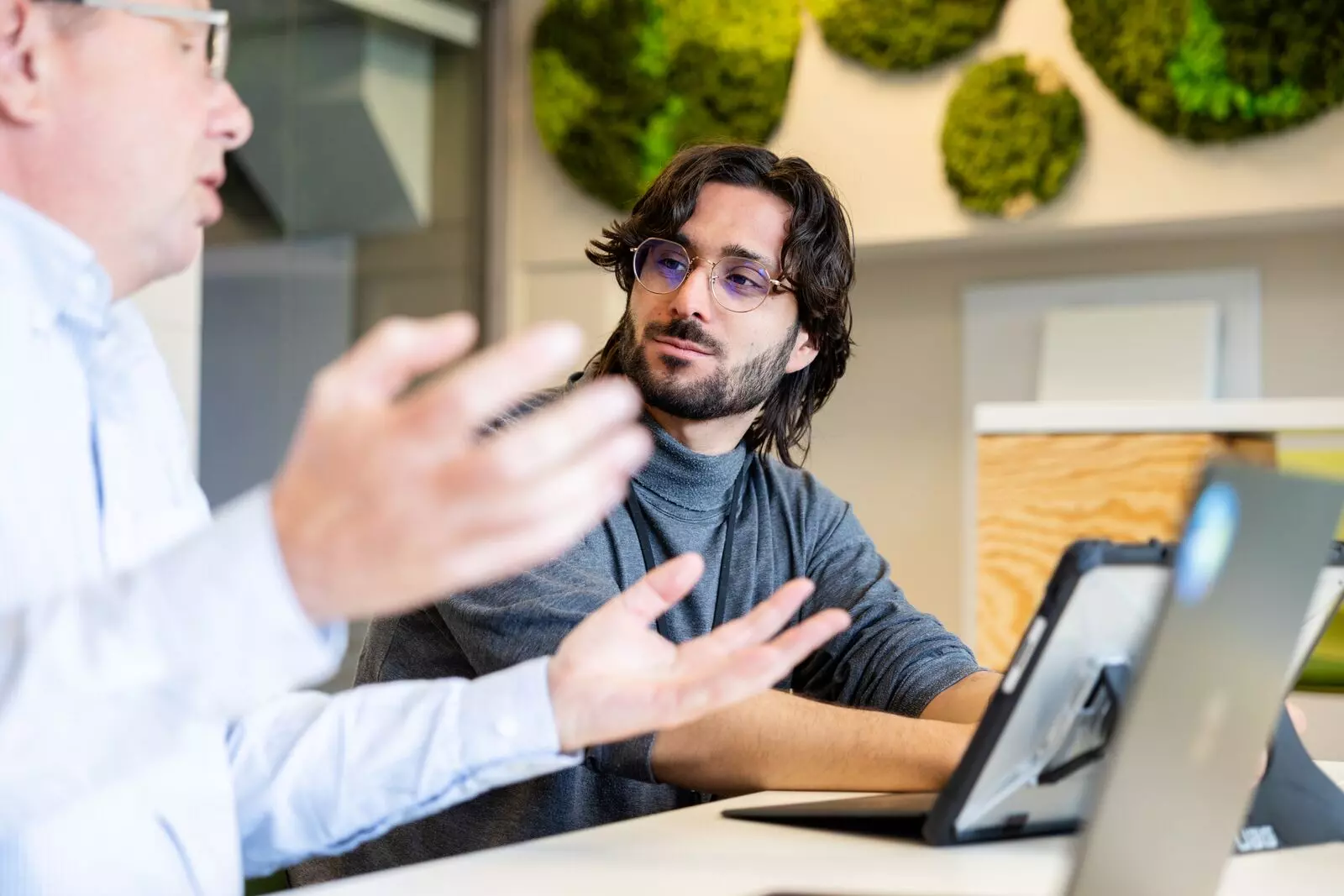 Lachende collega's van Woonstad in gesprek achter hun laptops. 